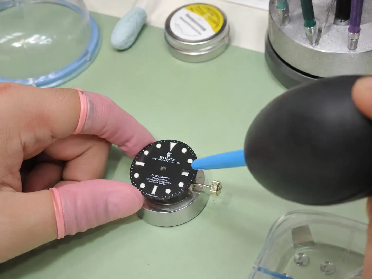 Quality control technician performing dust inspection on cased Clean Factory watch under specialized workbench illumination